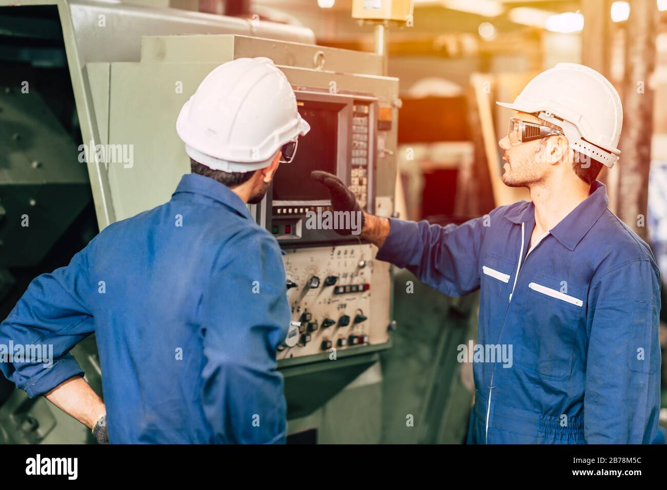 l'équipe d'ingénieurs de l'industrie qui enseigne aide un ami à utiliser la machine lourde de contrôle en usine Banque D'Images