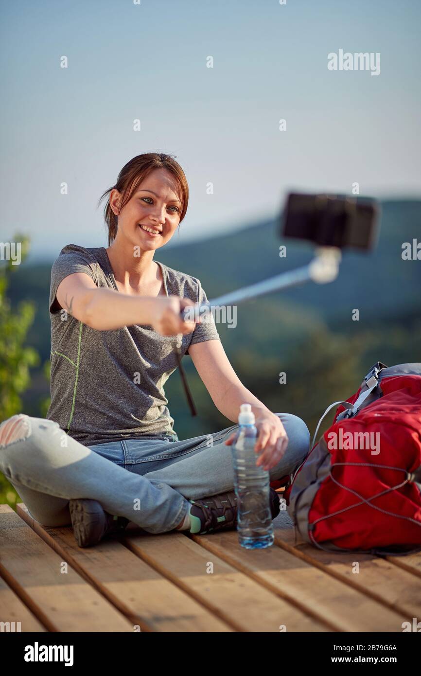 femme profitant de la nature, assis avec des jambes croisées au point de vue haut en montagne regardant le téléphone cellulaire, prendre selfie. nature, détente, loisir, po Banque D'Images