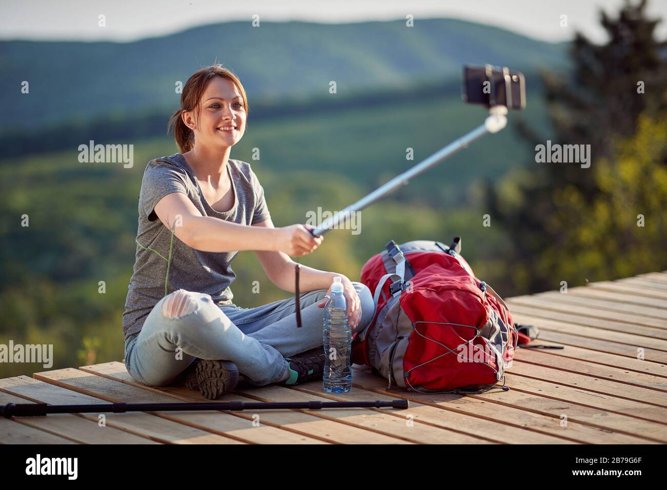 femme assise avec jambes croisées au point de vue haut en montagne regardant le téléphone cellulaire, prenant selfie. nature, détente, loisirs, positif, énergie conc Banque D'Images