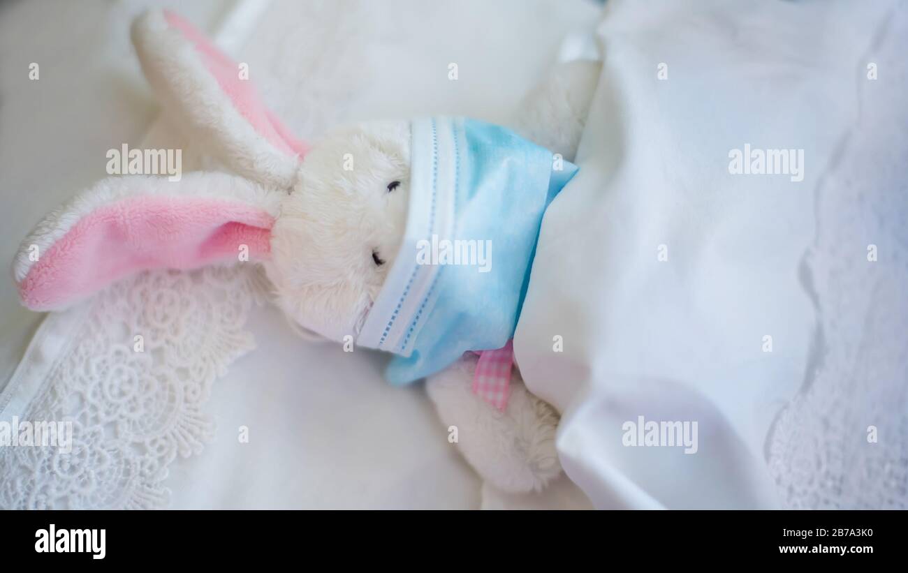 Le Lapin Dans Un Masque Medical Protecteur Se Trouve Dans Un Lit De Bebe Sur Un Lit Blanc Le Jouet Est Tombe Malade Medecin En Jeu Protection Contre Les Virus La Grippe