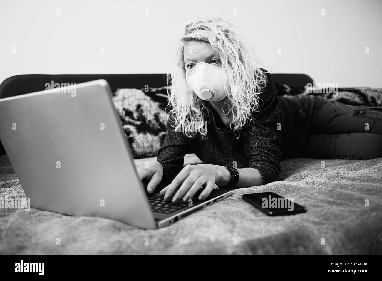 Femme en quarantaine pour Coronavirus portant un masque de protection et travaillant intelligemment Banque D'Images