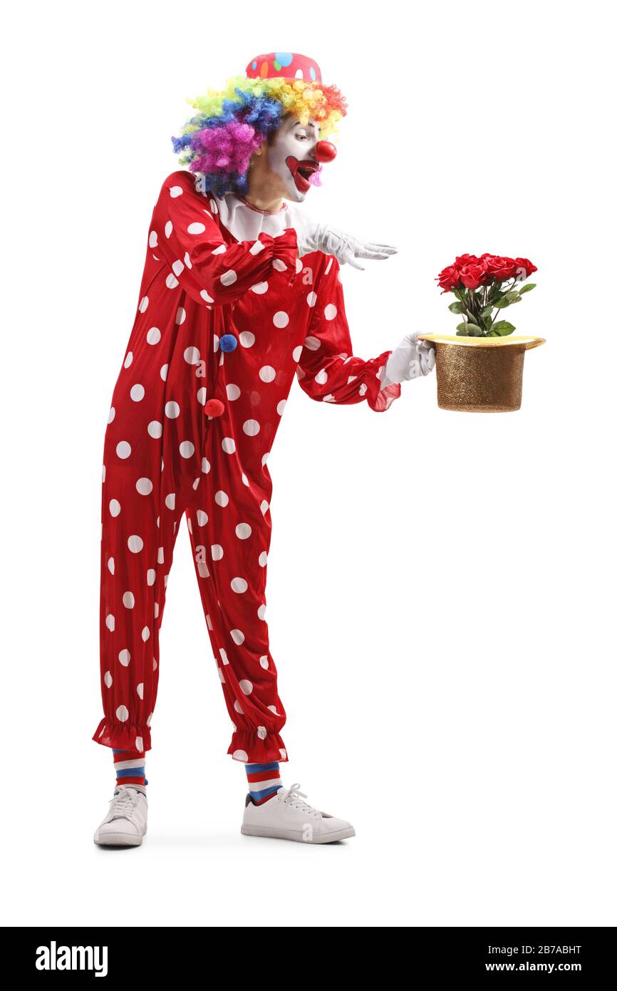 Tir sur toute la longueur d'une clown tenant un chapeau avec des roses rouges à l'intérieur isolé sur fond blanc Banque D'Images