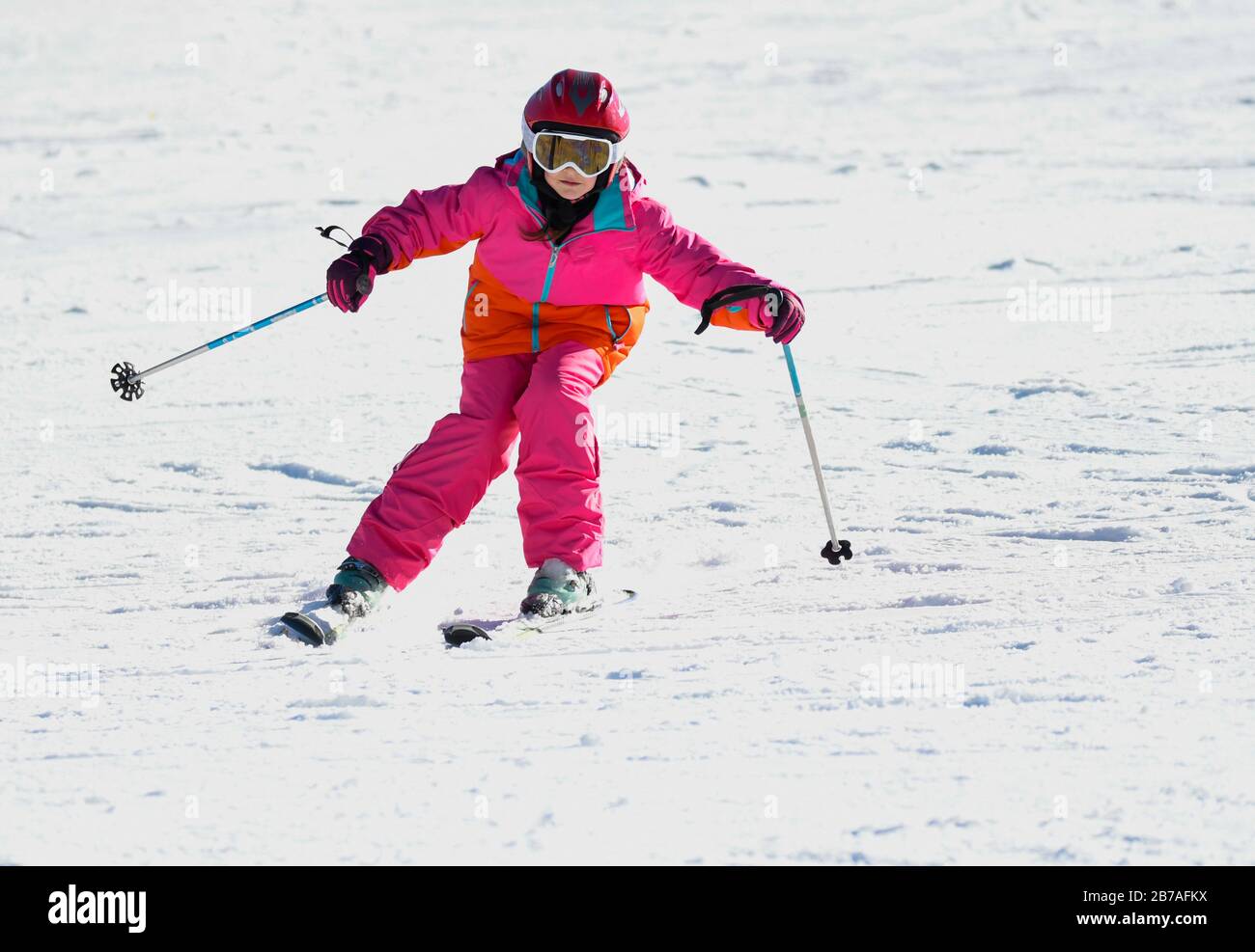 Girl en skis dans la neige molle sur une journée ensoleillée à la montagne, sur une pente raide. Banque D'Images