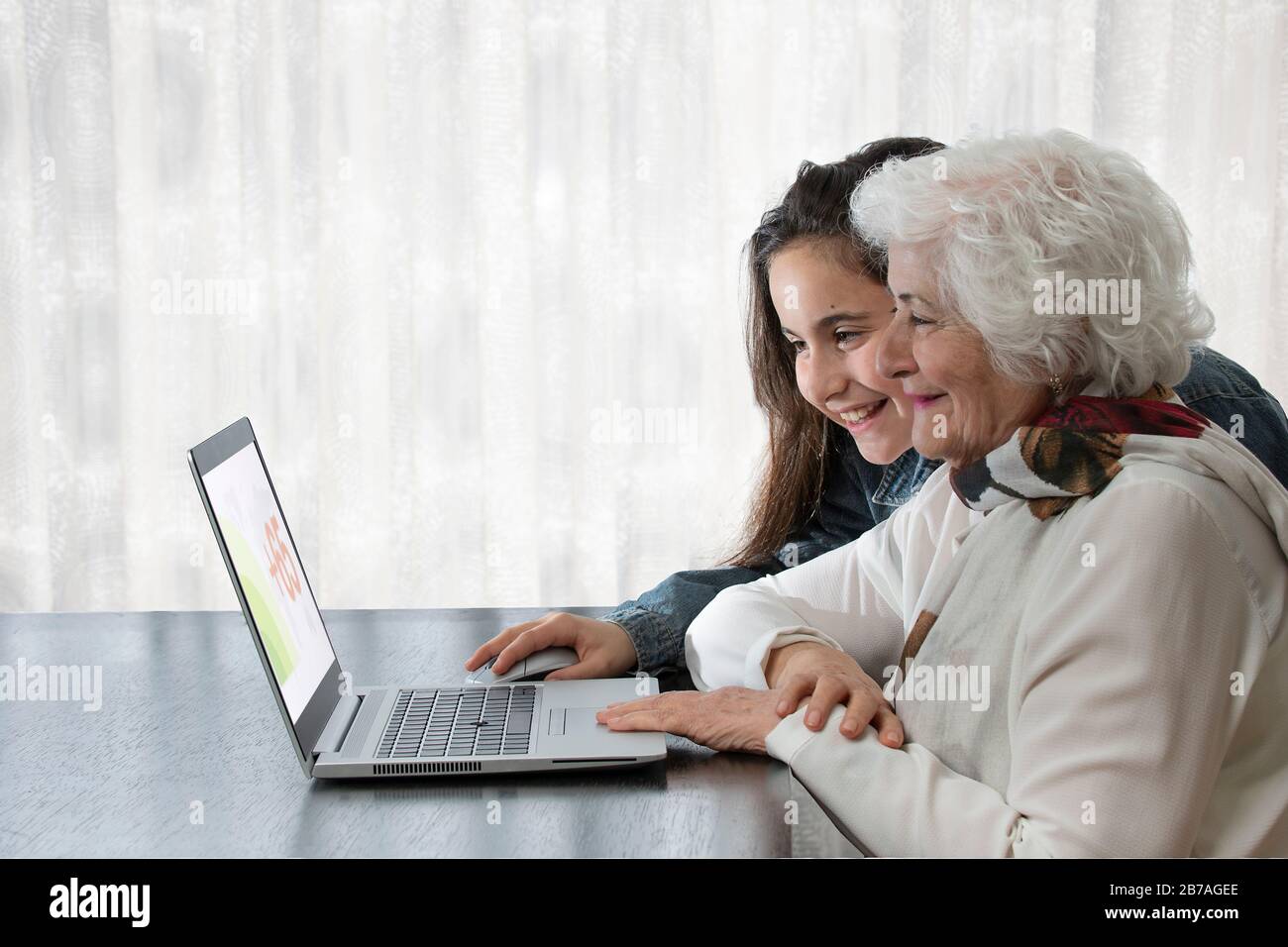 petite-fille enseignant à sa grand-mère d'utiliser un ordinateur sur une table en bois avec un mouchoir coloré. concept d'amour, d'amitié, de technologie, guérir Banque D'Images