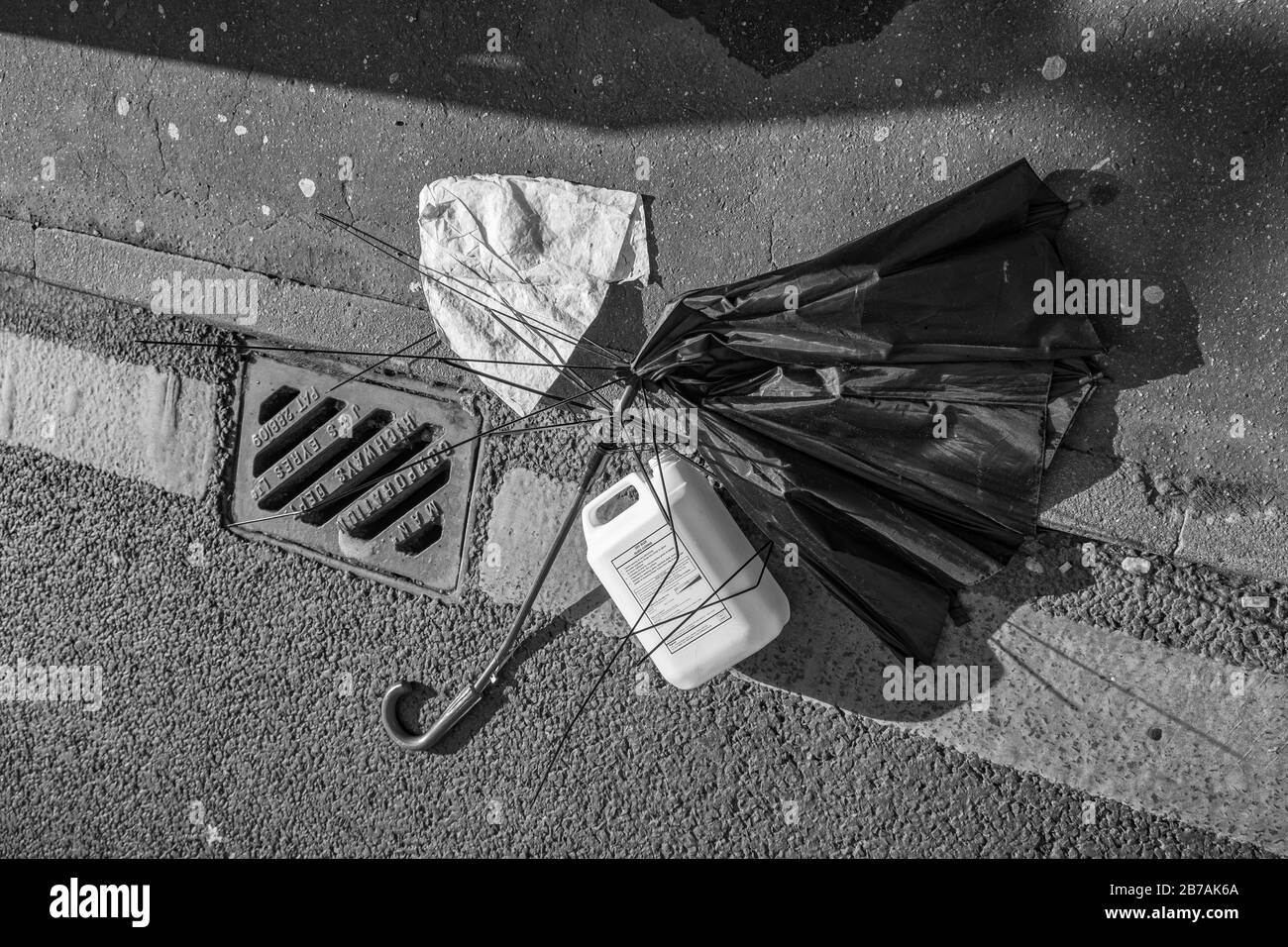 Manchester, Royaume-Uni - 1er mars 2020 : rupture du contenant de parapluie et de plastique sur le pavé après une tempête. Capturé en noir et blanc. Banque D'Images