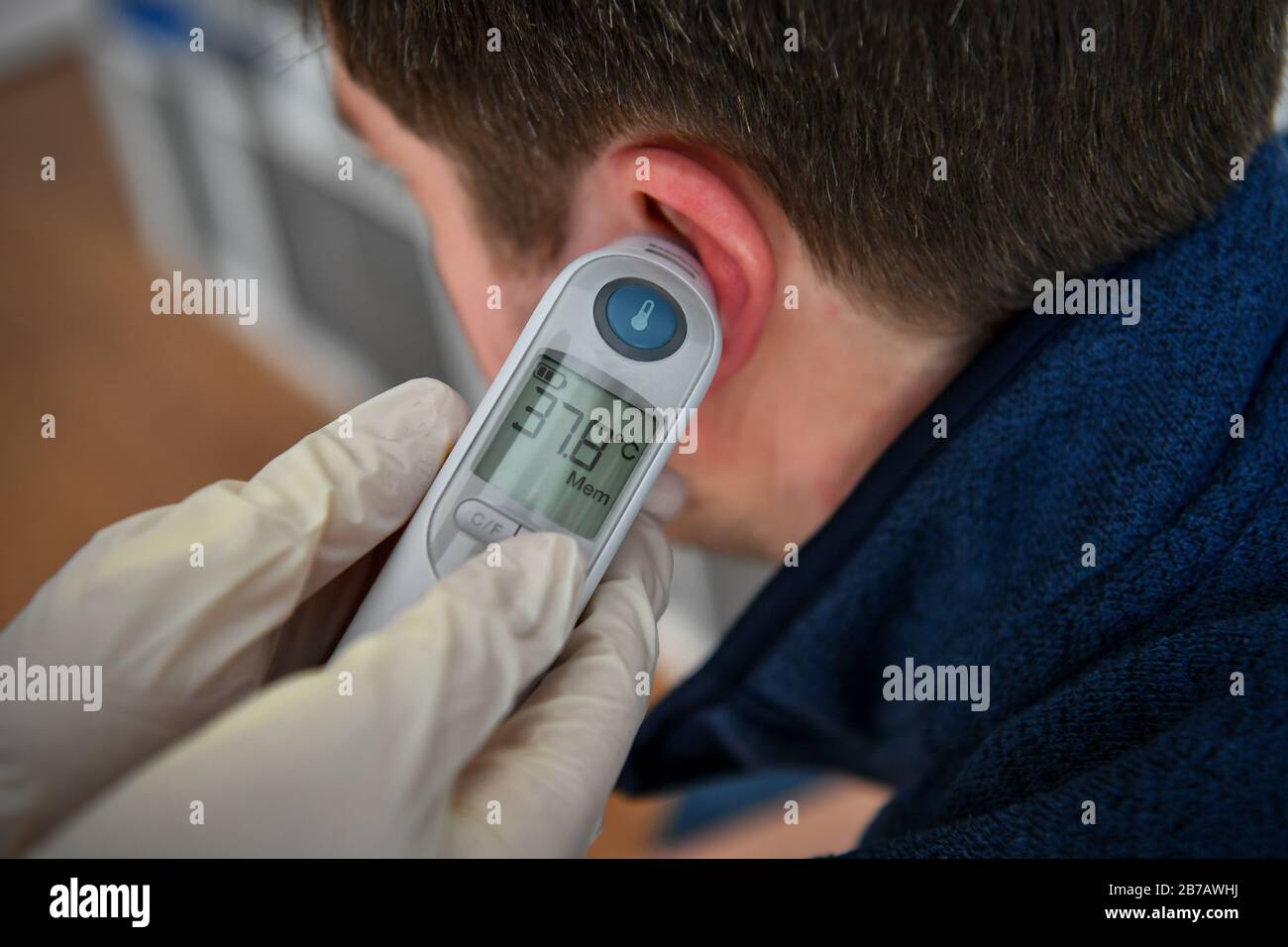 Image POSÉE PAR MODELA température corporelle de 37,8 degrés Celsius est  enregistrée sur un homme à l'aide d'un thermomètre tympanique. Photo PA.  Date De L'Image: Samedi 14 Mars 2020. Crédit photo devrait