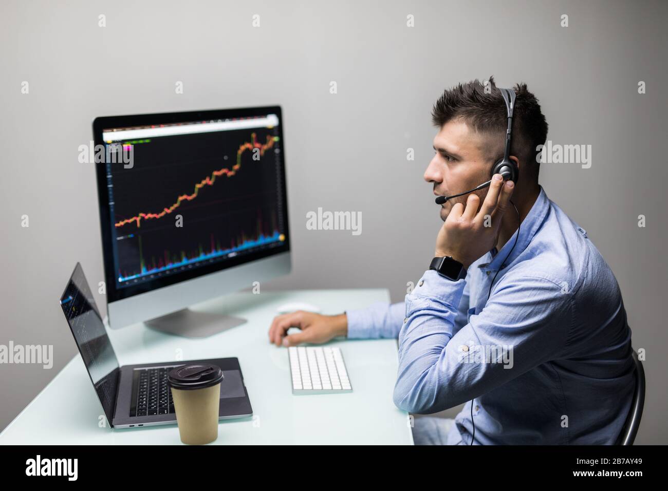 Vue latérale du courtier en bourse regardant des graphiques sur plusieurs écrans au bureau Banque D'Images