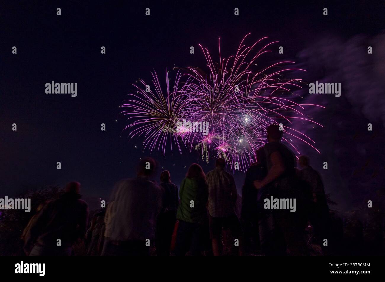 Belle scène de feu avec des gens comme silhoutes regardant aux roquettes violettes colorées au ciel de nuit. Banque D'Images