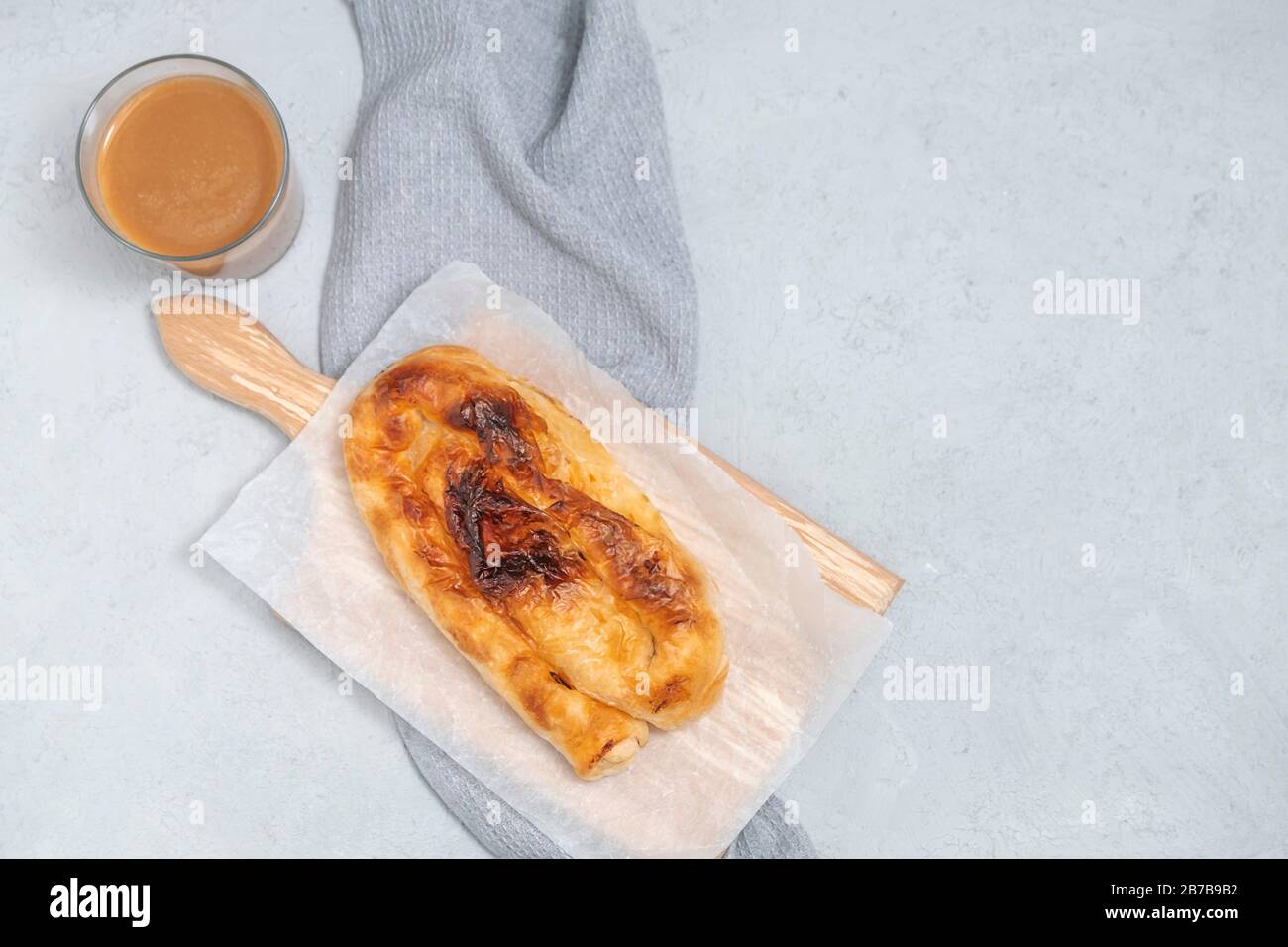 Au-dessus de la vue de la tarte au fromage bulgare Banitsa avec une tasse de boza sur fond neutre. Image avec espace de copie, plat Banque D'Images