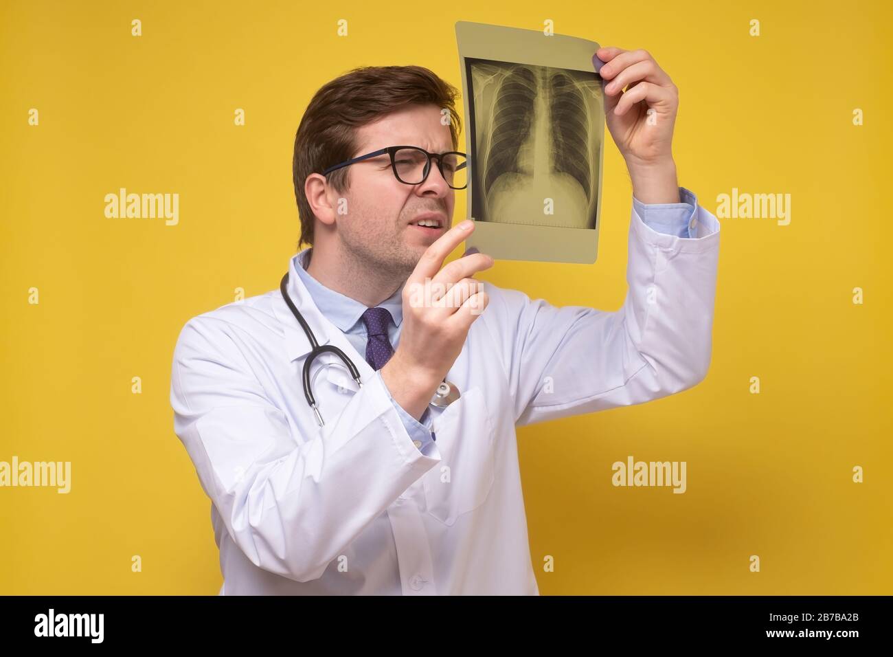 Le médecin traitant de l'image de rayons X des poumons se concentre sur l'image de rayons X soupçonnant la pneumonie. Studio tourné sur un mur jaune. Banque D'Images