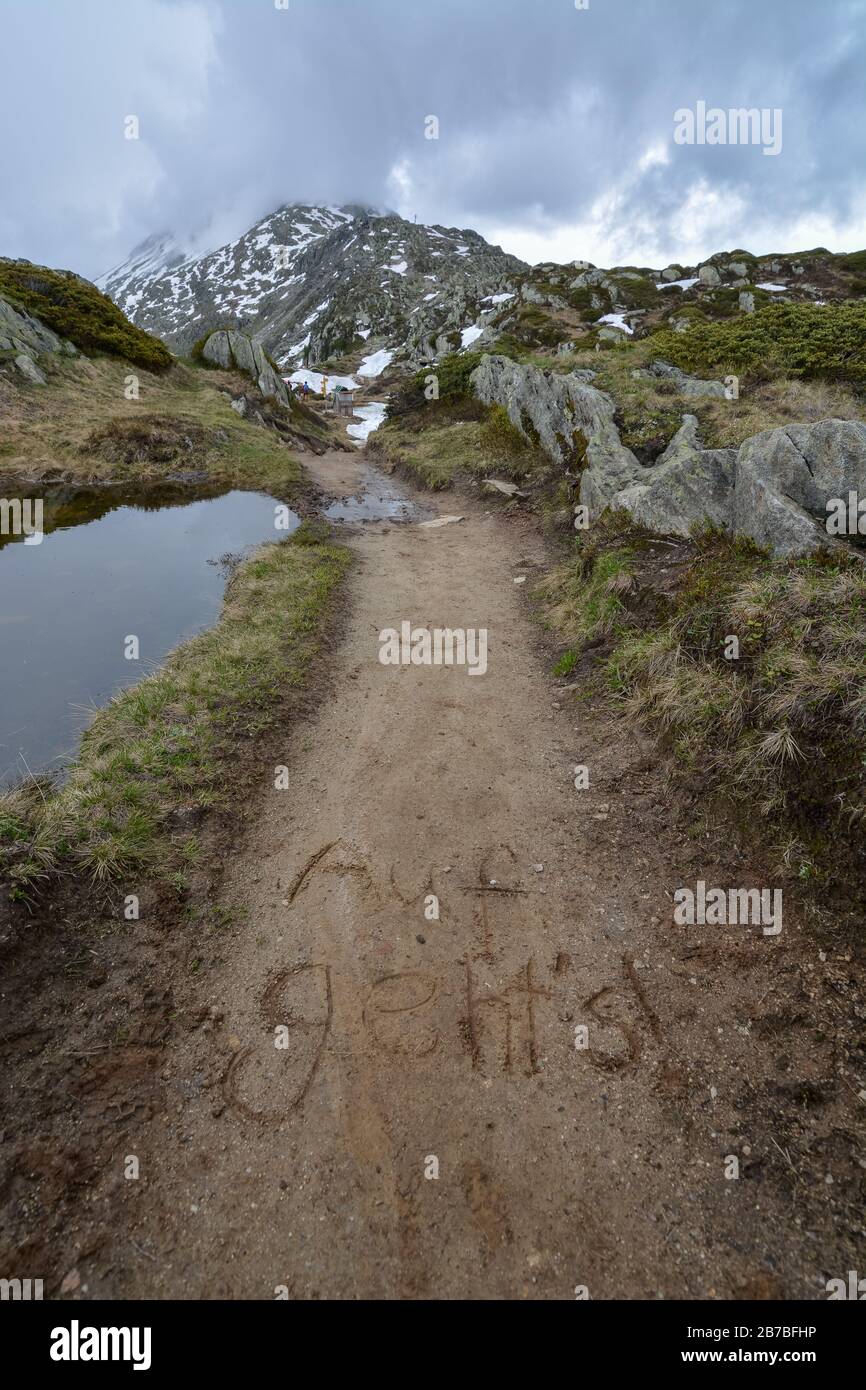 Un sentier avec les mots allemands Auf geht écrit dans la boue près du glacier d'Aletsch dans les alpes suisses un jour ensoleillé Banque D'Images