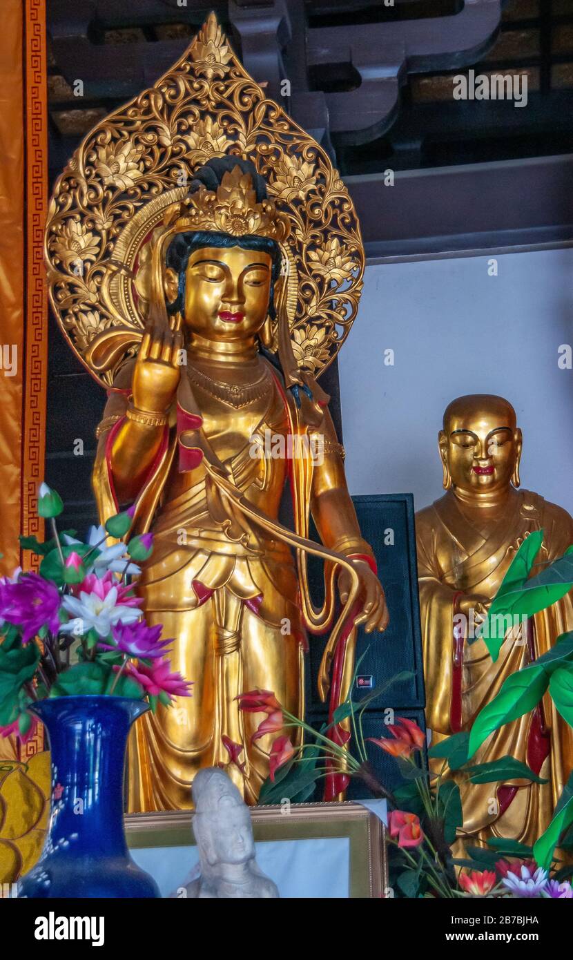 Guilin, Chine - 11 mai 2010 : Temple bouddhiste Qixia dans le parc Seven Star. Gros plan de la statue dorée de la déesse Guan Yin. Fleurs autour et Saint d'or Banque D'Images