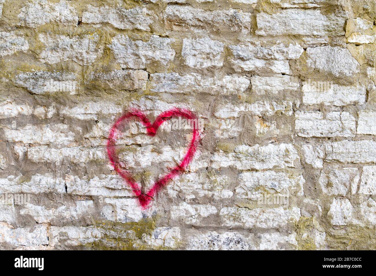 Symbole cœur rouge peint sur un mur de briques. Banque D'Images