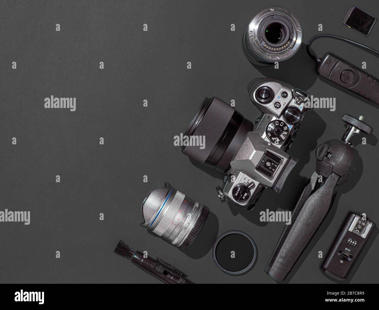 Espace de travail photographe avec appareil photo reflex numérique, objectif, tablette à stylet et accessoires pour appareil photo sur fond noir. Appareil photo, photographie, concept de contenu visuel. Vue de dessus ou de la couche plate. Espace de copie. Lumière dure. Banque D'Images