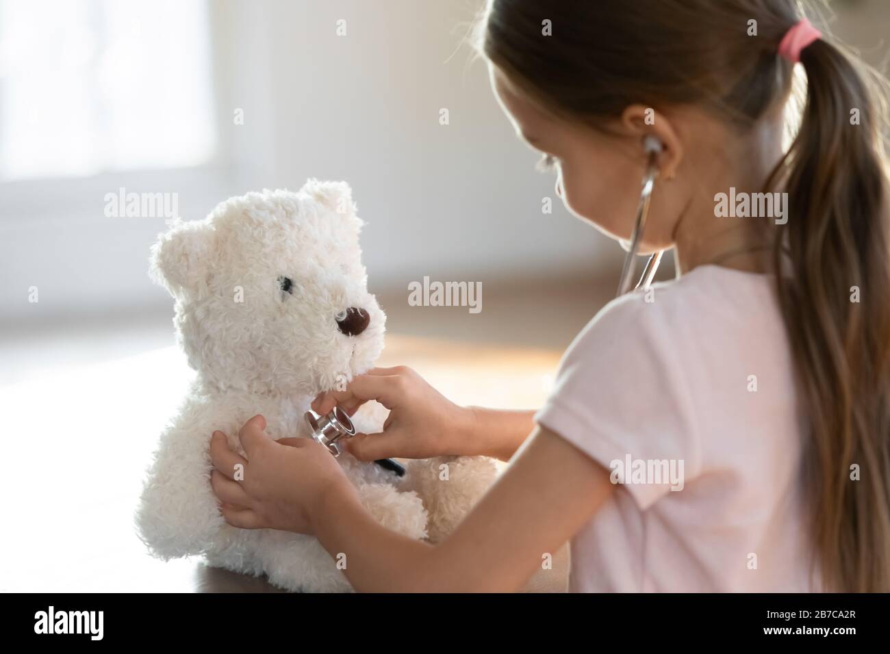Curieux petit enfant d'âge préscolaire jouant infirmière patient avec jouet. Banque D'Images