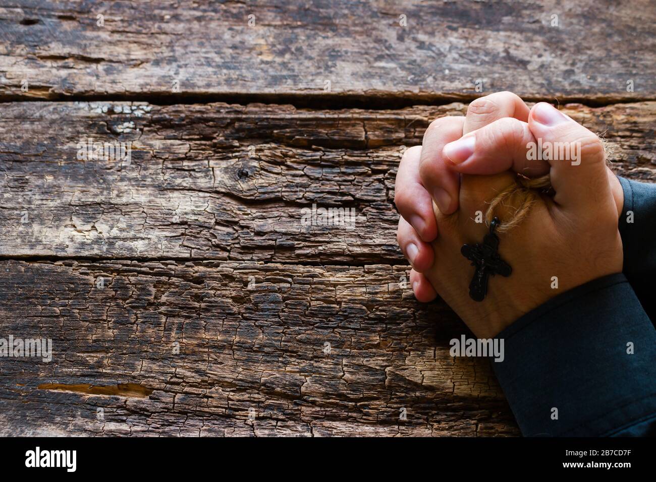 homme priant avec une croix dans ses mains sur le fond en bois avec de l'espace pour le texte Banque D'Images