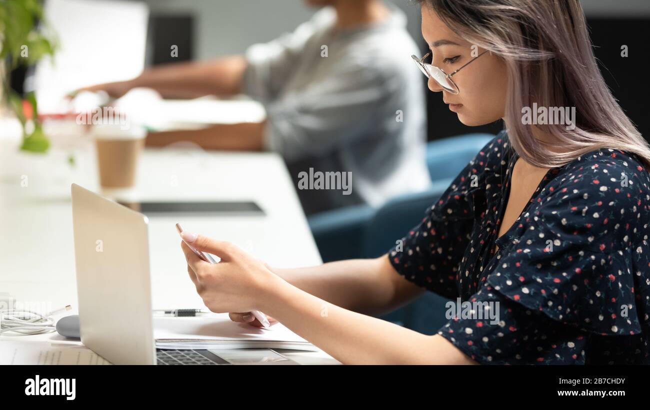 Femme d'affaires asiatique portant des lunettes à l'aide d'un téléphone, lisant un e-mail professionnel Banque D'Images