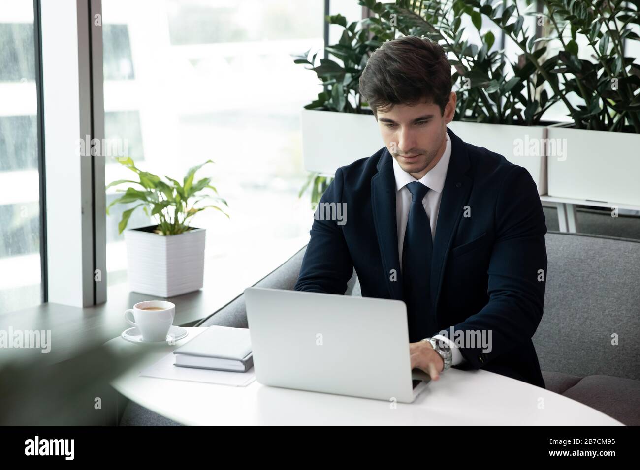 Les hommes s'assoient au bureau sur un ordinateur portable Banque D'Images
