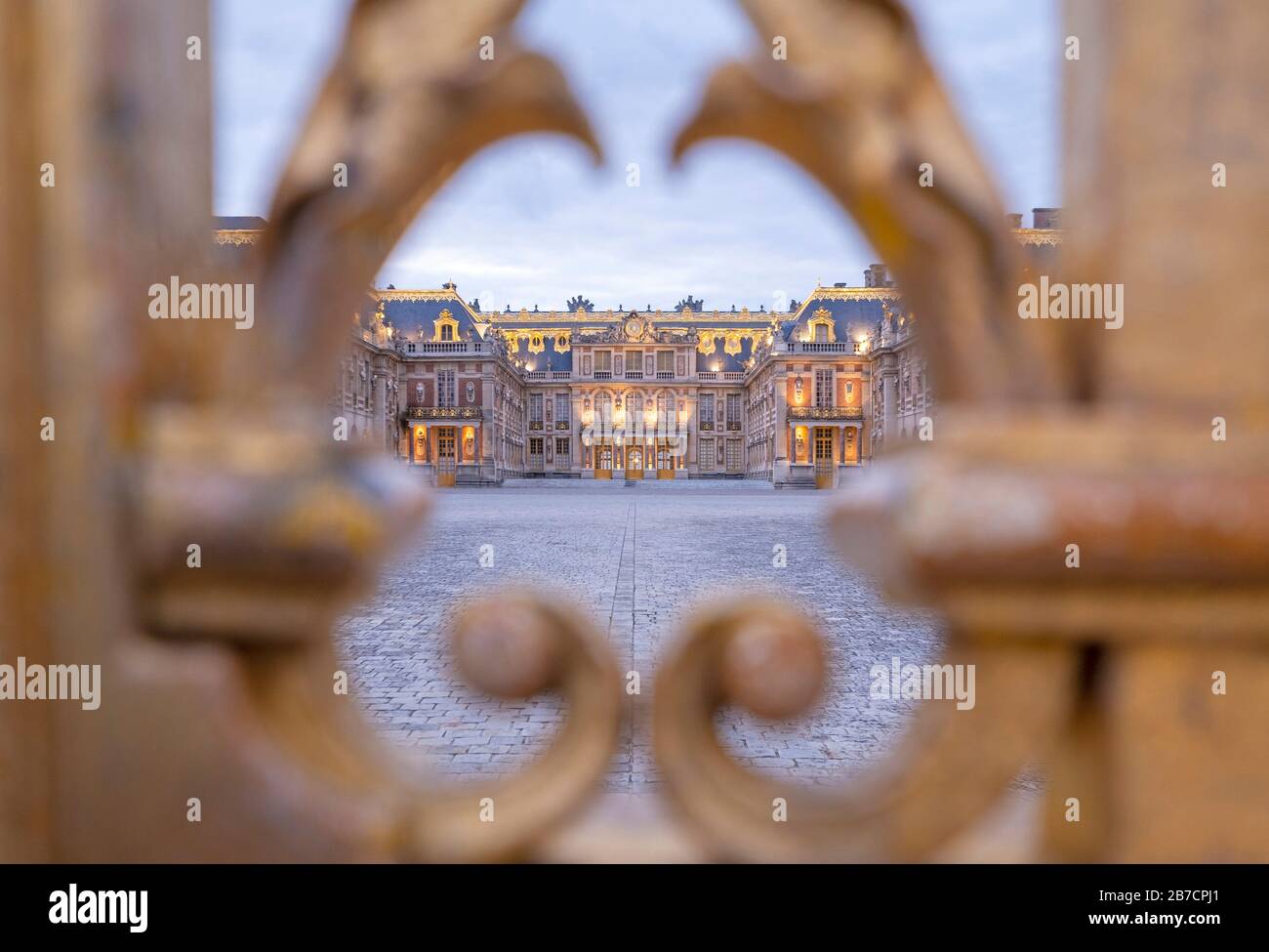 La façade est du château de Versailles vue à travers les bars dorés de la porte d'entrée, France Banque D'Images