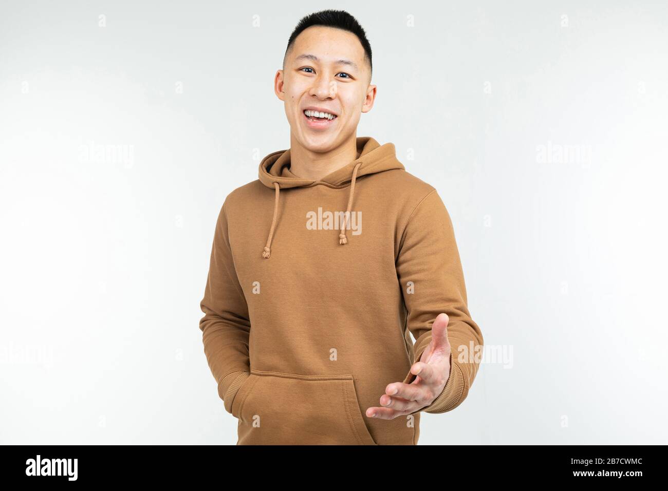 Homme asiatique dans le hoodie brun avec des bras ouverts sur un fond blanc Banque D'Images