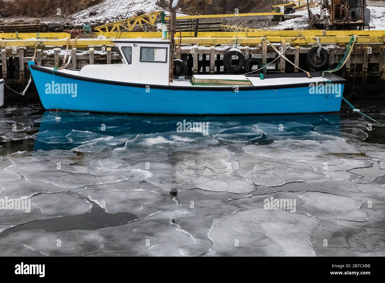 Glace de mer près de la rive sur une baie ouvrant sur l'océan Atlantique, avec un bateau de pêche, à Terre-Neuve, au Canada Banque D'Images