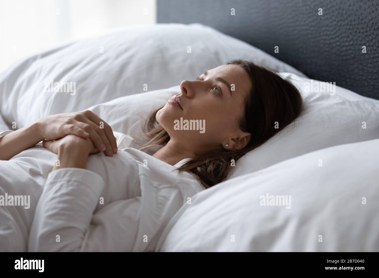 Jeune femme mécontente posée au lit souffrant d'insomnie. Banque D'Images