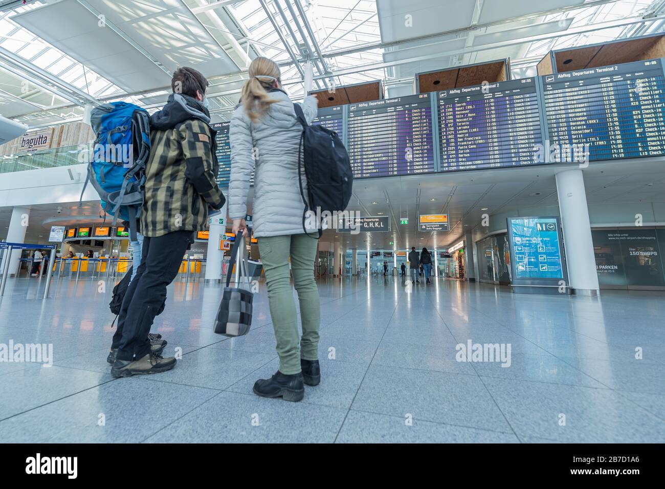 Munich, Allemagne - 15 mars 2020: Petit groupe avec masques de visage à l'aéroport de Munich vide de vérifier les vols Banque D'Images