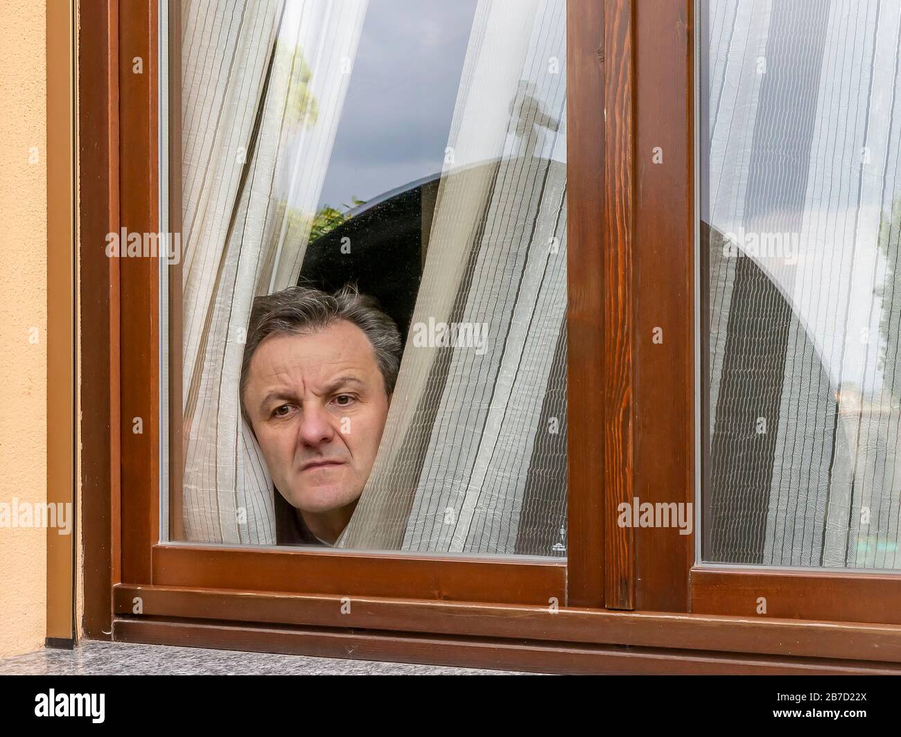 L'homme italien forcé de rester en quarantaine à cause du covid-19 du coronavirus à travers la fenêtre avec une expression disconsolate Banque D'Images