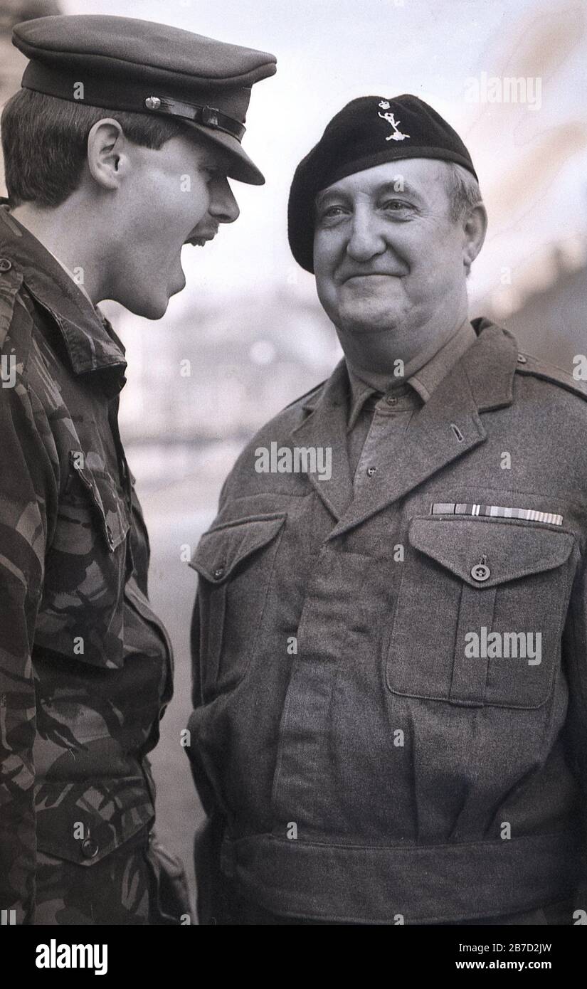 1980, historique, jeune officier de l'armée en robe militaire moderne, ordres de 'barking' à un soldat plus âgé, portant l'uniforme traditionnel, et béret, Angleterre, Royaume-Uni. Banque D'Images