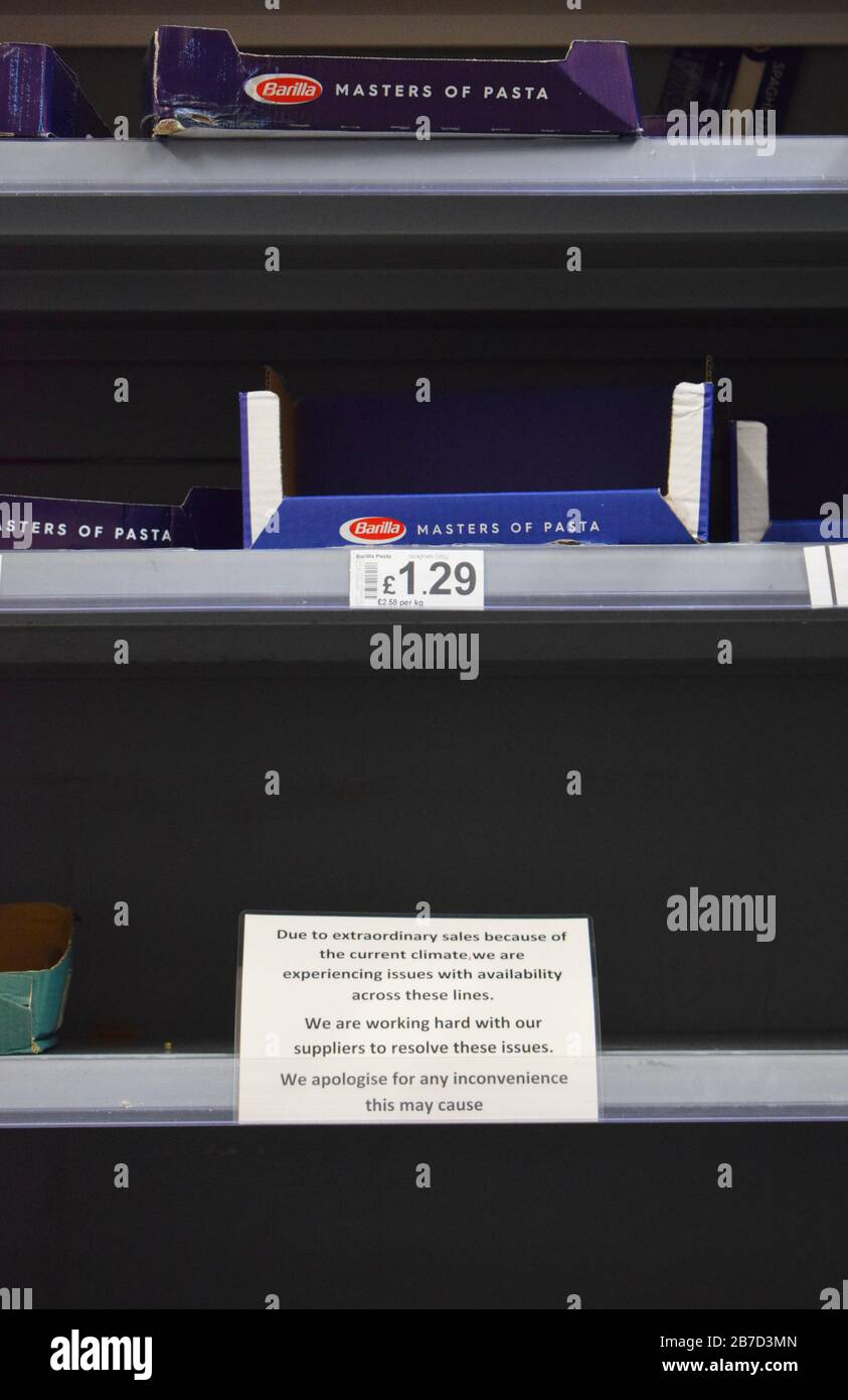 Vider les étagères à pâtes dans un supermarché britannique avec un signe s'excusant à mesure que l'achat de panique / stockage des aliments secs / longue vie augmente en raison du coronavirus Banque D'Images