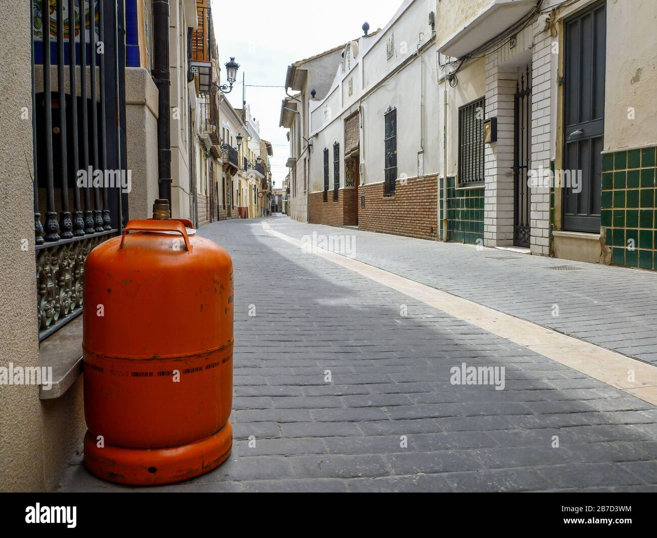 Bouteille de gaz orange dans une rue calme d'un village Banque D'Images