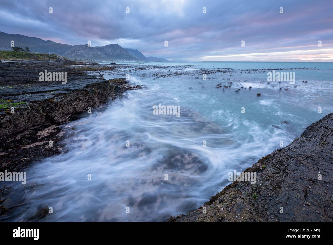 Un magnifique paysage marin tôt le matin photographié lors d'une journée de tempête au lever du soleil à Hermanus, en Afrique du Sud. Banque D'Images