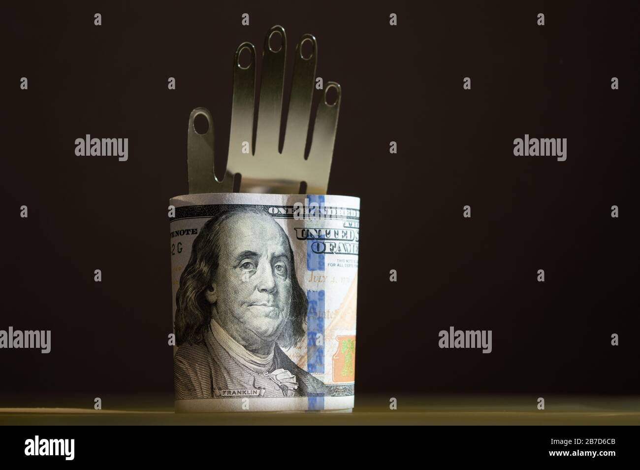 Dollars américains, tenant à la main de métal sur le fond sombre. Photo conceptuelle, design minimaliste Banque D'Images