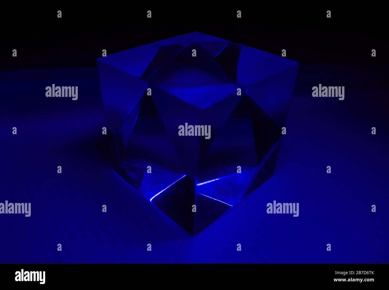 Un cube transparent éclairé de lumière bleue. Banque D'Images