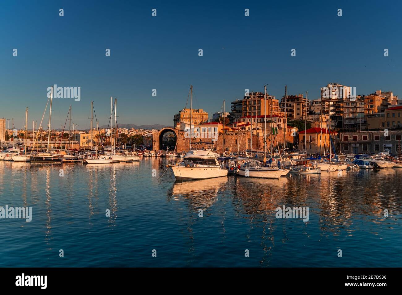 Vue panoramique sur le magnifique coucher de soleil dans la forteresse de Koules (Rocca a Mare), île de Crète. Yachts reflétant dans le miroir de l'eau près du vieux port vénitien Banque D'Images