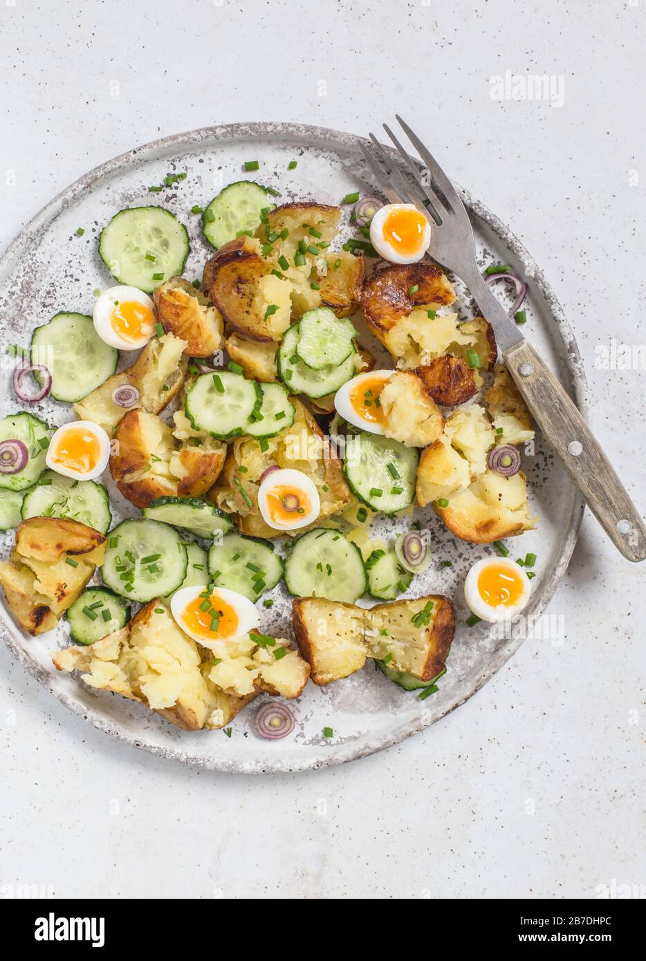 Salade de pommes de terre rôties, concombre et œufs de caille, servie sur une plaque grise. Banque D'Images