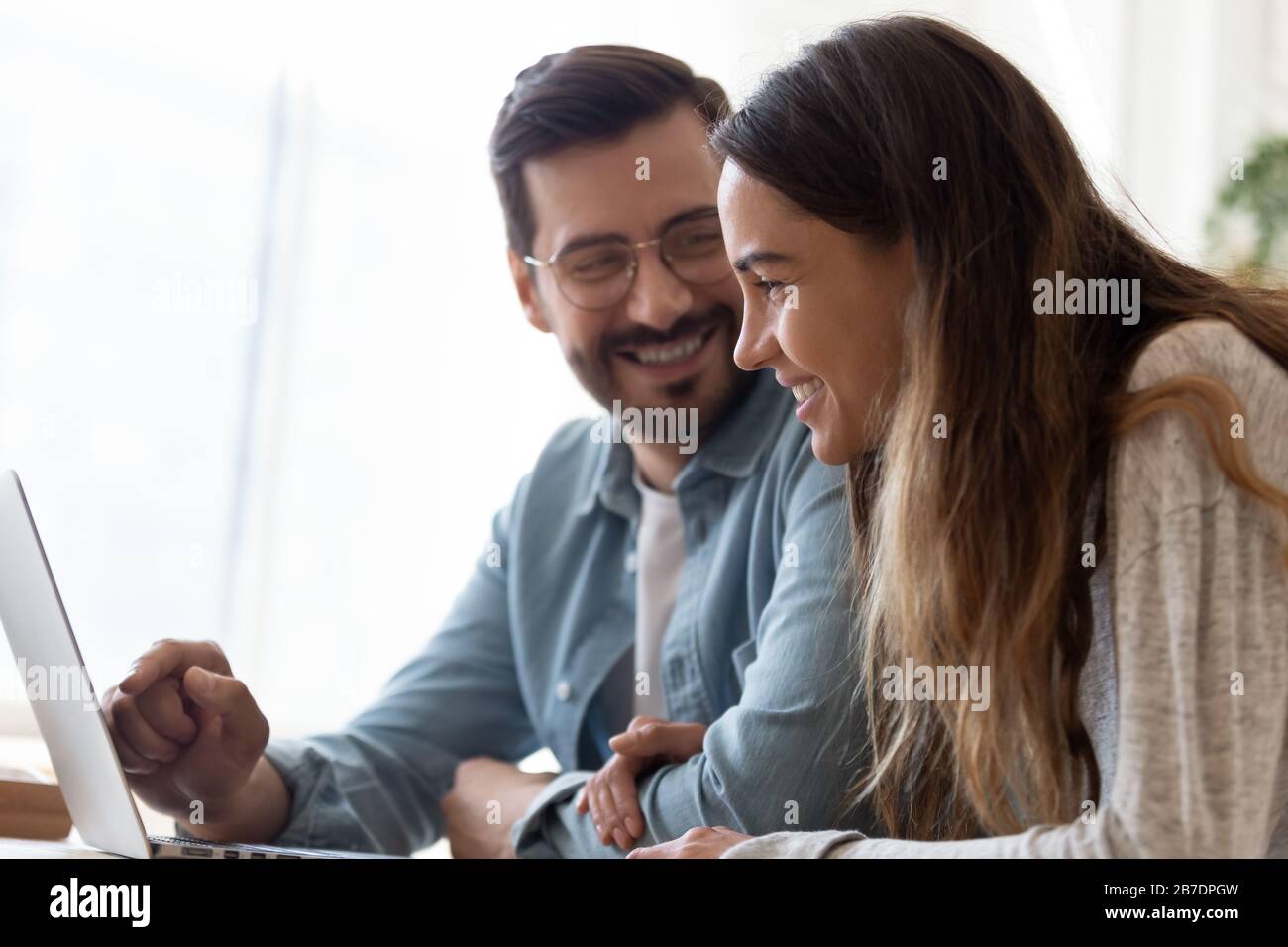 Heureux couple aimant utilisant l'ordinateur portable ensemble, tenant les mains Banque D'Images