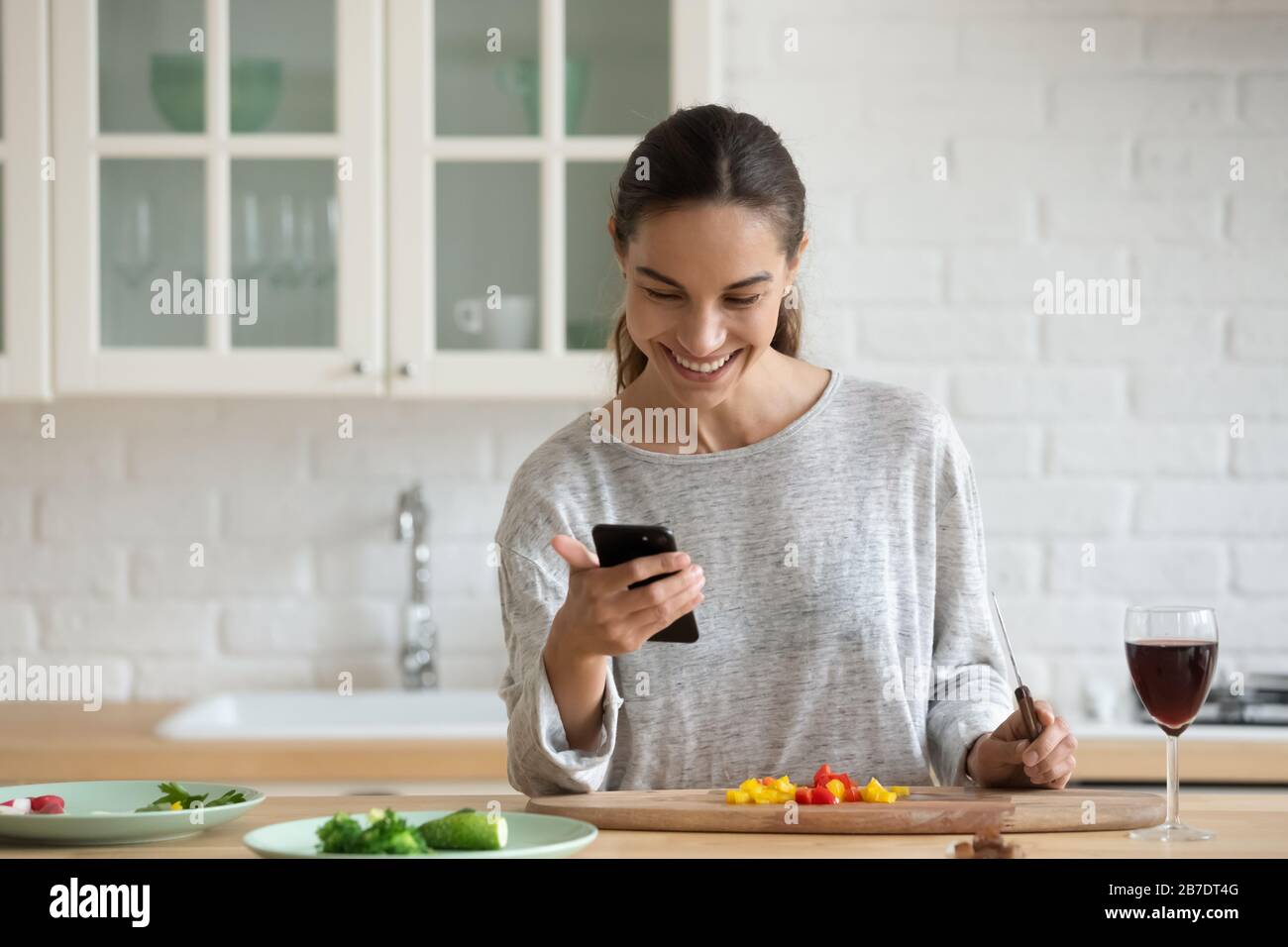 Femme souriante avec smartphone, salade de cuisine, collation saine Banque D'Images