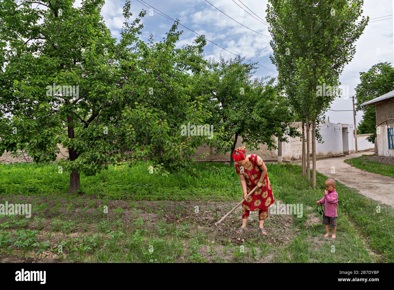 Femme ouzbek travaillant sur le terrain avec son enfant à côté, à Rishtan, en Ouzbékistan. Banque D'Images