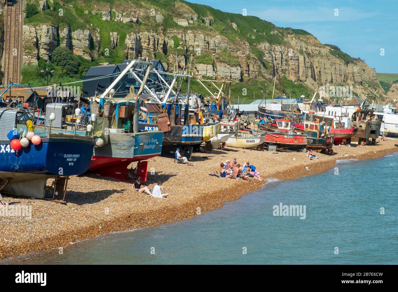 Hastings, les gens qui bronzer sur la plage de bateaux de pêche de la vieille ville de Stade à Rock-A-Nore, East Sussex, Royaume-Uni Banque D'Images