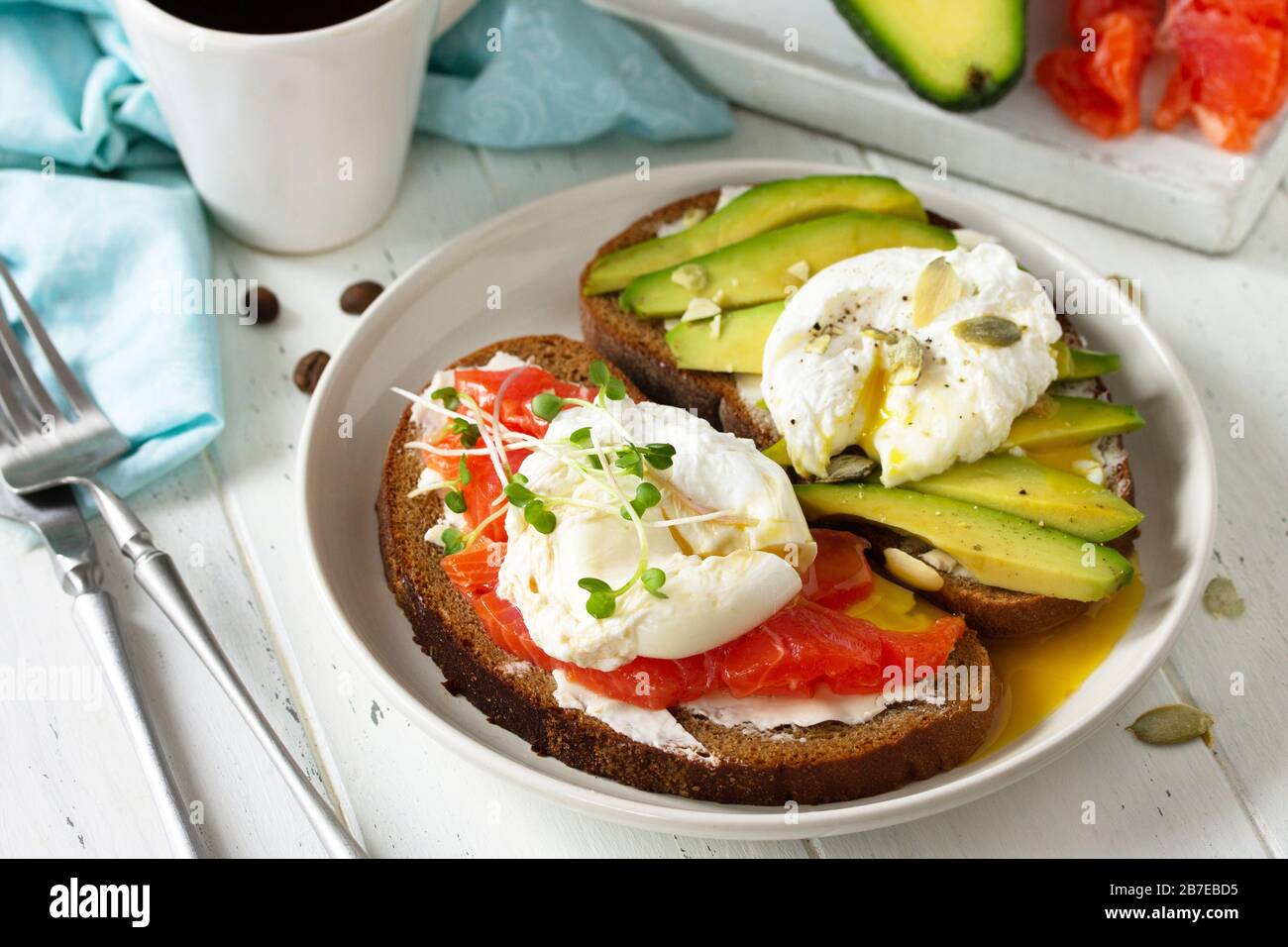 Petit-déjeuner le matin. Sandwich cuit aux œufs poché avec avocat, saumon et café sur une table en bois. Banque D'Images