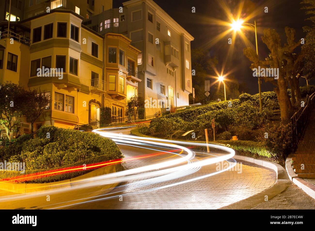 Twisted Lombard Street la nuit avec des sentiers de feux de voiture à San Francisco. Les sentiers de lumière blanche et rouge se recourent autour du coin. Banque D'Images