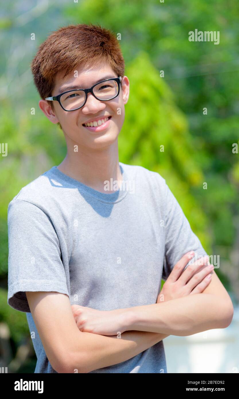 Un beau adolescent asiatique portant des lunettes bras croisés, un jeune  homme hipster joyeux et joyeux au portrait regarde et sourit avec un visage  heureux au parc Photo Stock - Alamy