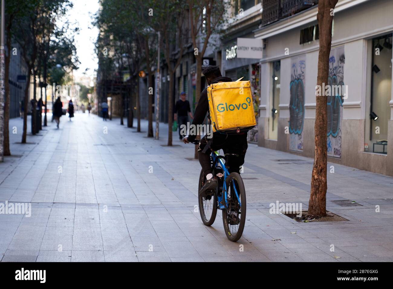 Un motard de livraison Glovo descend normalement occupé Calle Fuencarral, il est principalement des marcheurs de chien et des gens de livraison hors pendant l'état d'urgence Banque D'Images