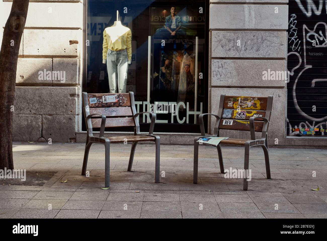 Deux chaises vides, l'une avec un journal abandonné dans une rue commerçante normalement occupée (Calle Fuencarral) Madrid. État d'urgence du virus Corona Banque D'Images