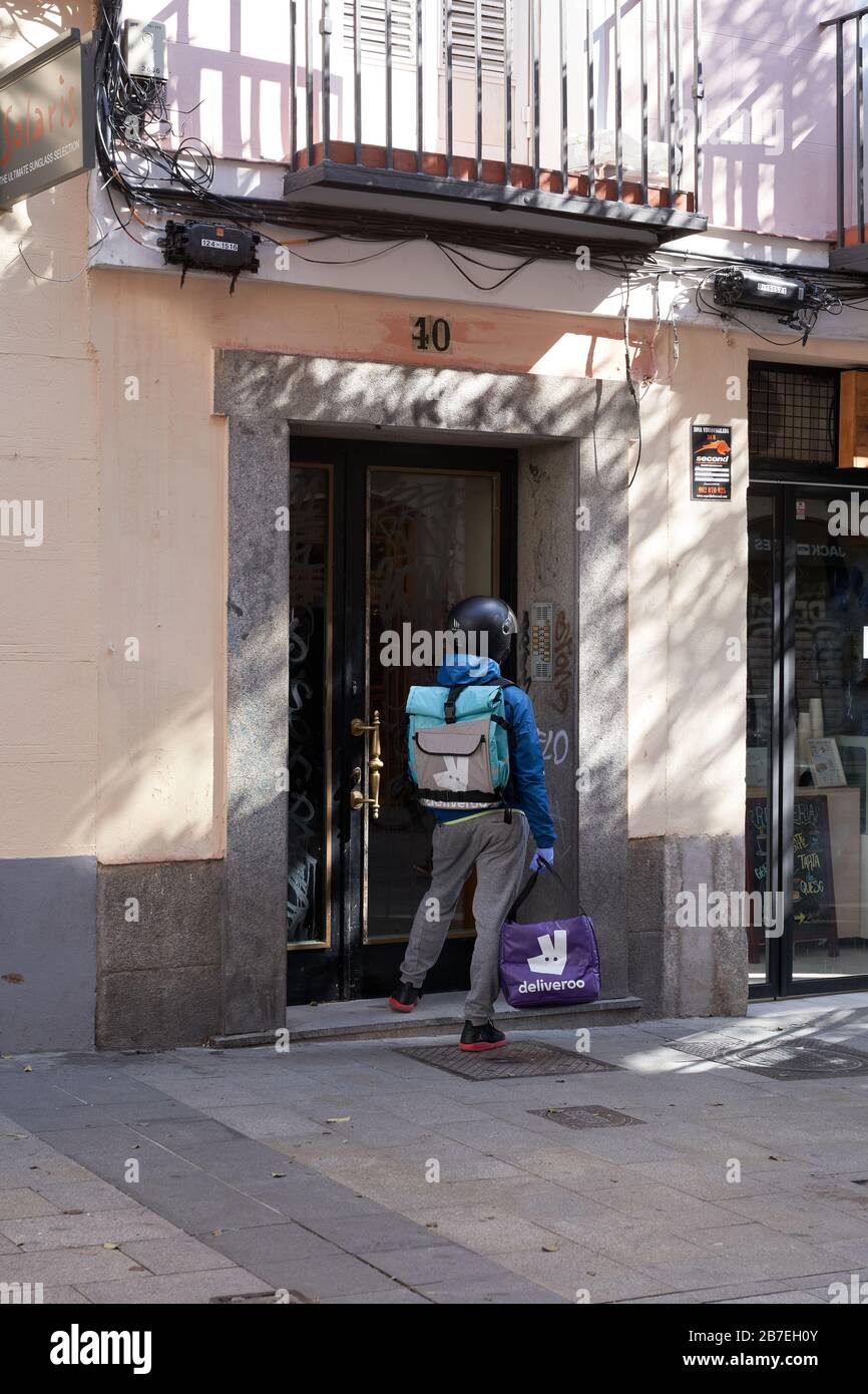 Un livreur de biker fait une livraison à un immeuble d'appartements dans le centre de Madrid pendant l'état d'urgence du virus corona Banque D'Images Un livreur de biker fait une livraison à un immeuble d'appartements dans le centre de Madrid pendant l'état d'urgence du virus corona Banque D'Images