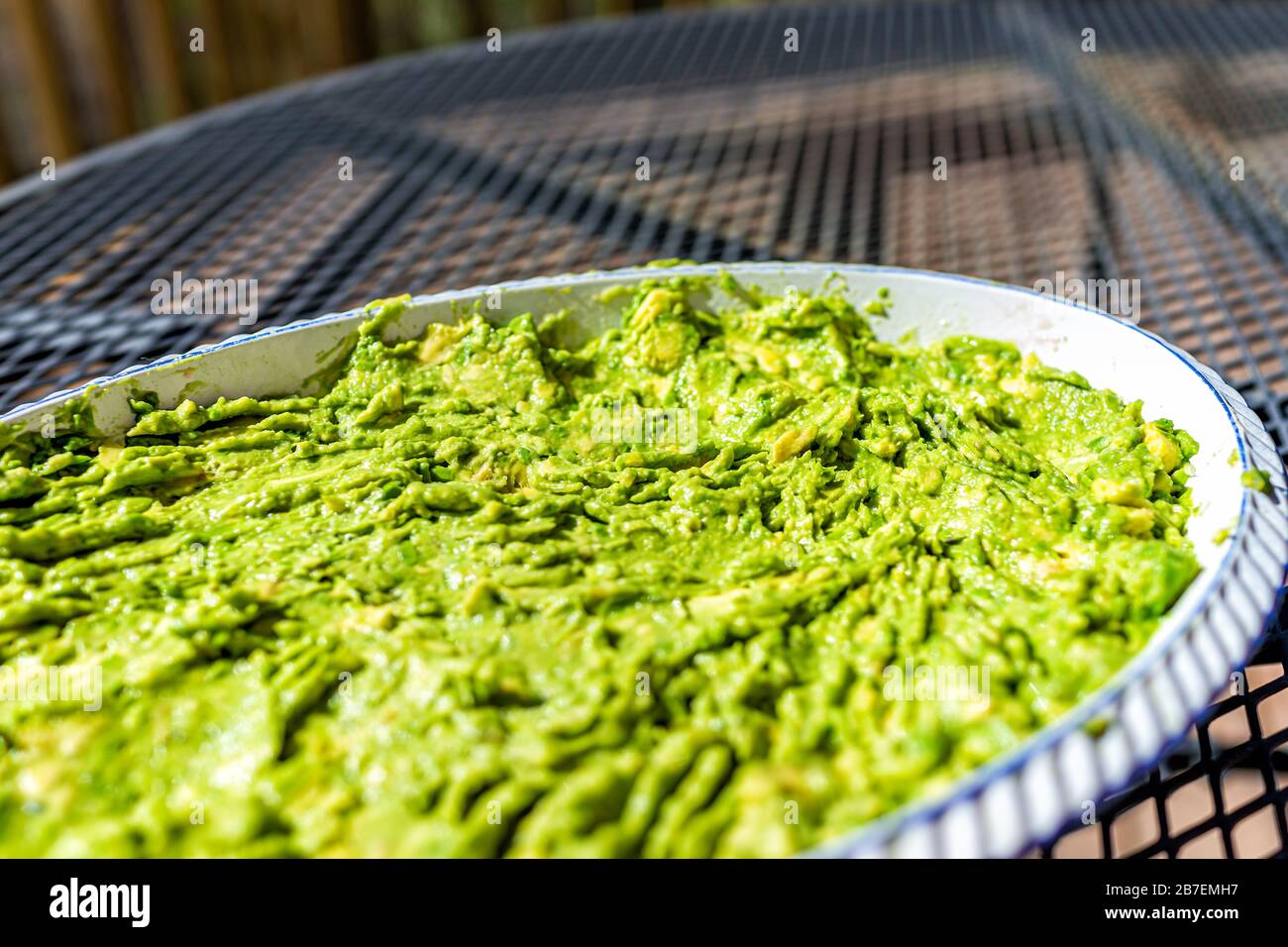 Table extérieure en métal sur terrasse et grand plat de guacamole dans plateau de service avec couleur vert avocat pour plateau de fête Banque D'Images