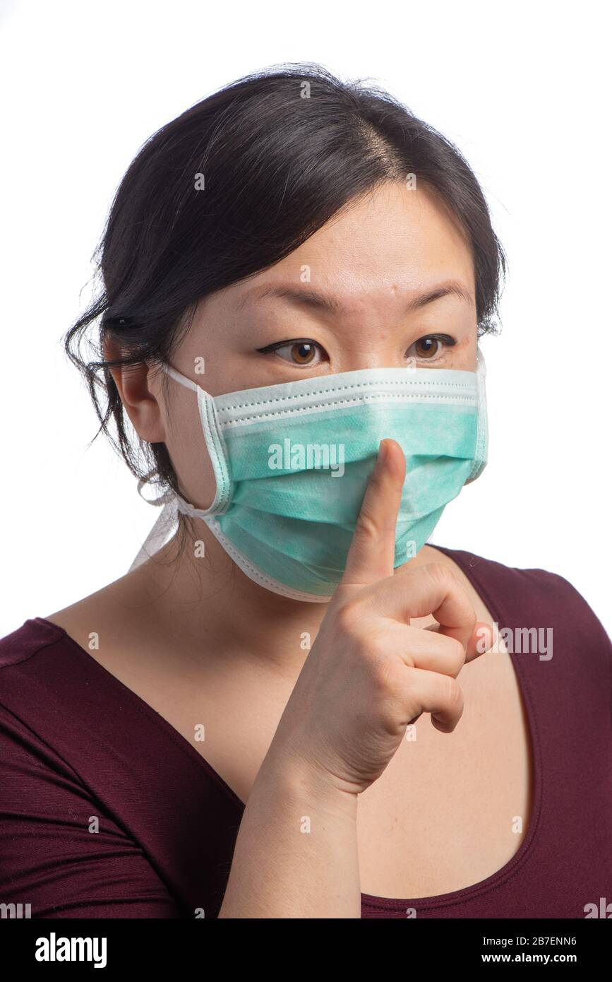 une jeune femme asiatique portant un masque de protection vert avec des gants médicaux qui se cachent sur un fond blanc Banque D'Images