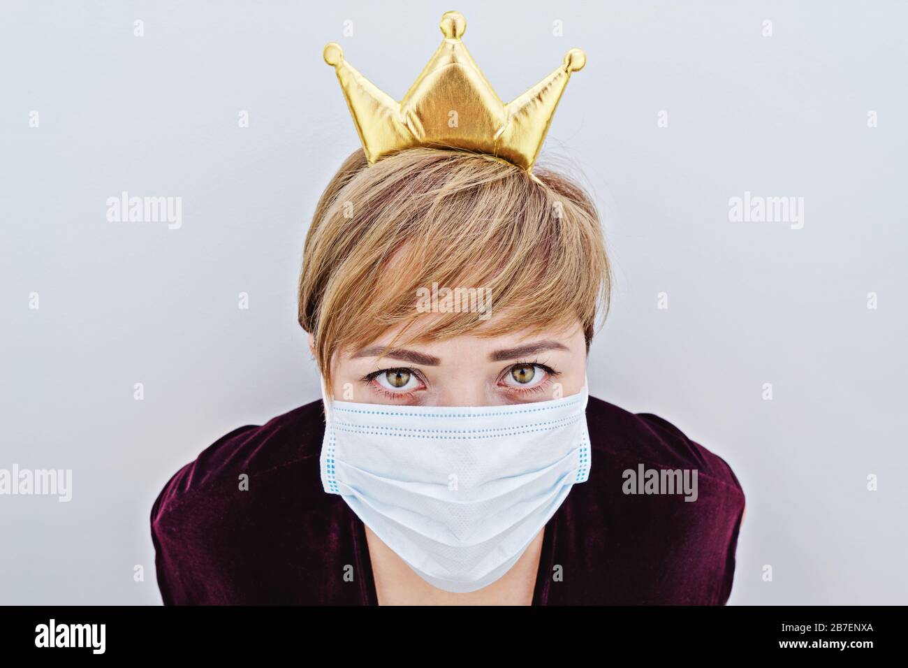 Gros plan portrait d'une femme portant une couronne sur sa tête et masque de protection regardant l'appareil photo. Panique chez les gens lors de la propagation du coronavirus Covid-19 dans le monde entier Banque D'Images