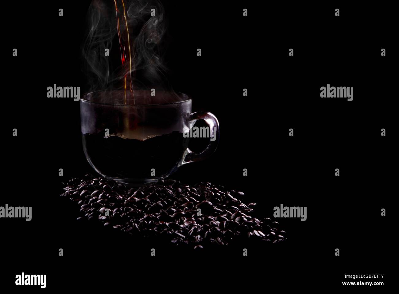 Du café chaud est versé dans une tasse sur fond noir. Banque D'Images